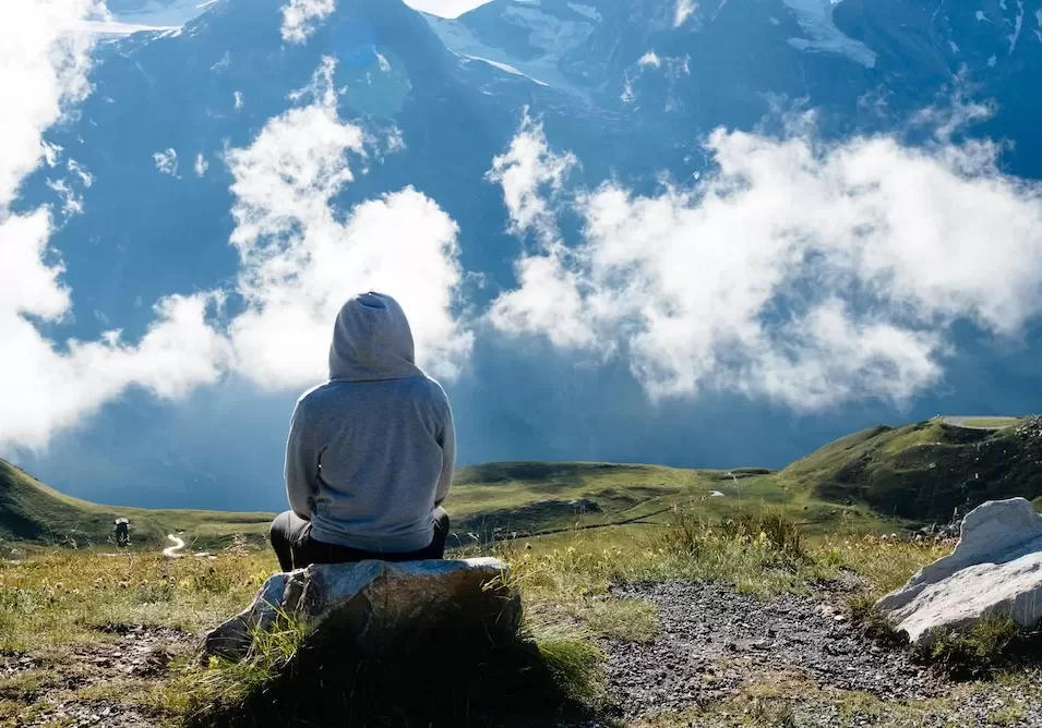 Young woman sitting looking at sea of clouds in mountain landscape Young woman sitting looking at sea of clouds in mountain landscape. Rear view. Grossglockner, Austria.